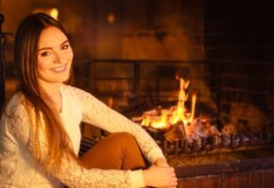 Smiling woman sitting beside fireplace